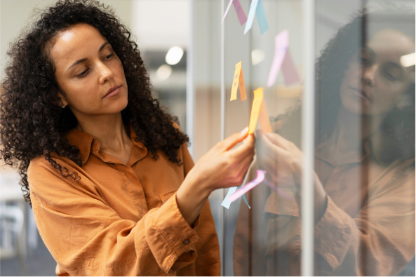 A person places sticky notes on an office board