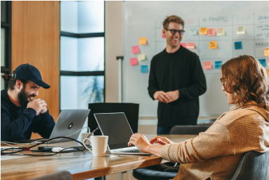 Explore scrum certifications Coworkers collaborate with laptops in a conference room