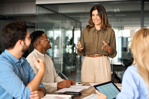 A businessperson presents to a group of colleagues in a room