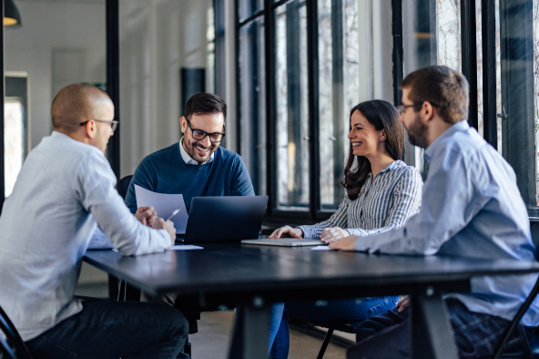 Colleagues speak joyfully around a table