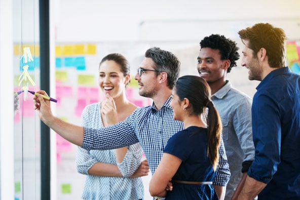 A group of colleagues writes on a transparent work board