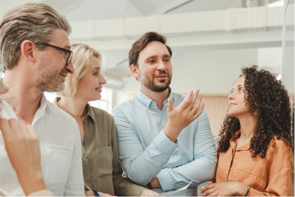 A group of coworkers stands in a huddle and converses