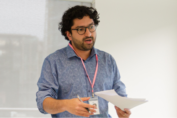 A person with a workplace badge and papers presents