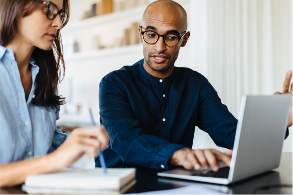 Colleagues collaborate at a desk with a laptop