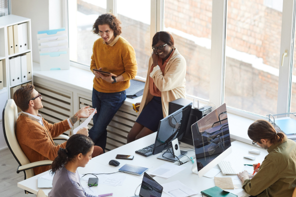 A group of colleagues gathered around computer monitors