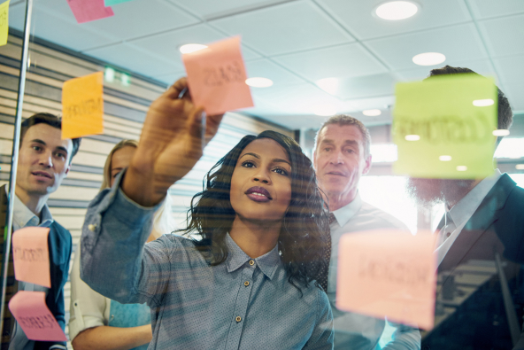 A woman using a glass work board with sticky notes