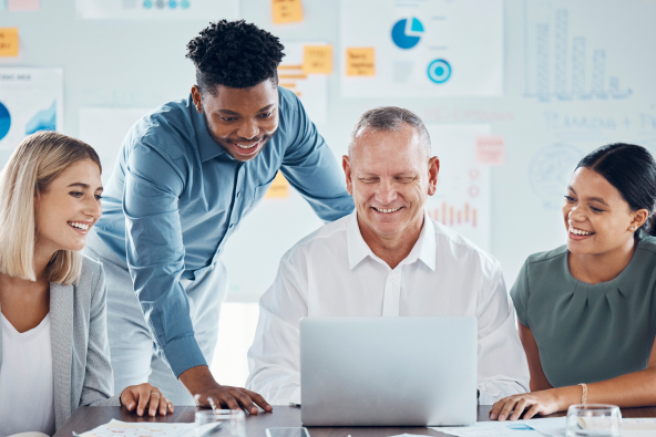 Four professionals working at a computer