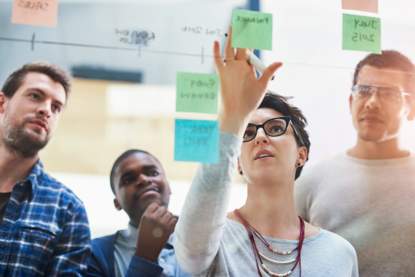 4 professionals reviewing notes on a board