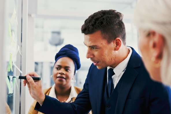 3 professionals reviewing sticky notes on a board